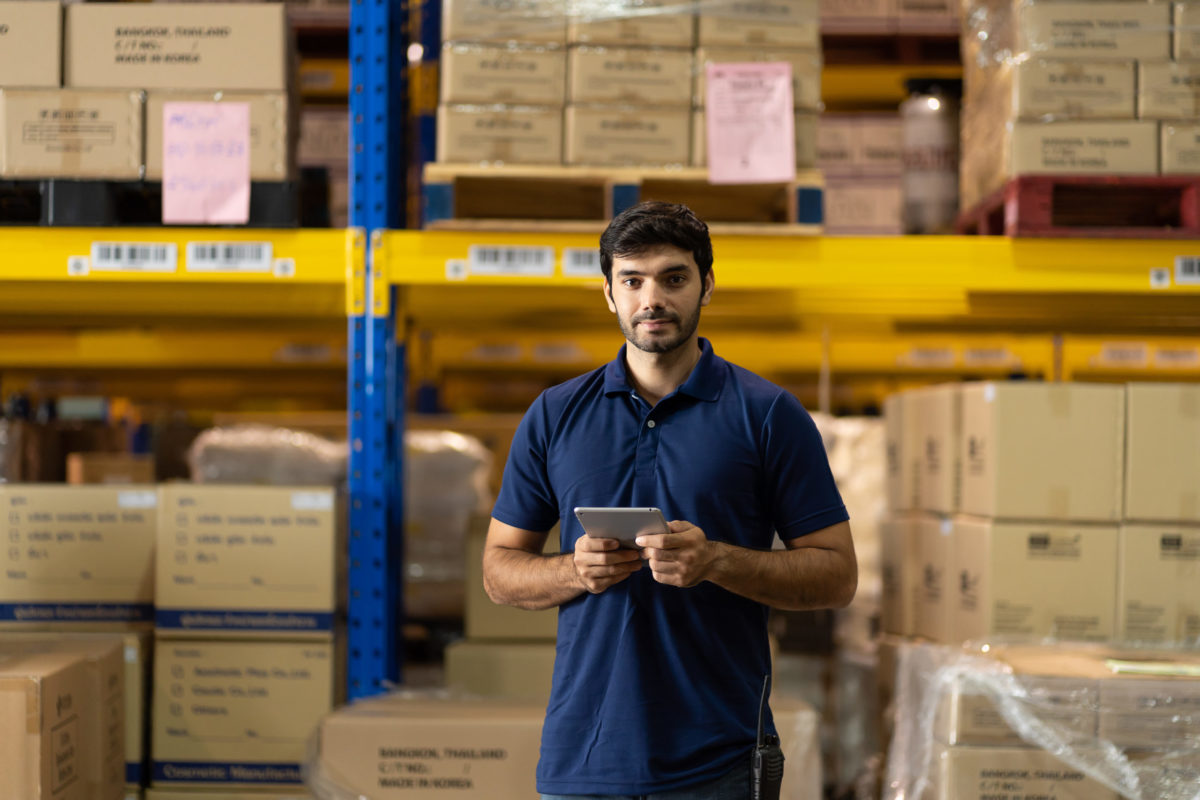 Portrait of warehouse male worker using digital ipad to make purchases for procurement.